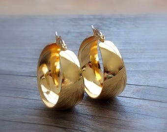 Puede incluir: Un par de pendientes de aro de oro pulido con un diseño de banda ancha y gruesa. El texto ONE DAY IN NEW YORK está impreso en letras pequeñas y claras sobre los pendientes. Cuentan con un mecanismo de cierre de bisagra.