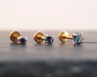 Puede incluir: Tres piezas de joyería corporal de oro con piedras preciosas iridiscentes. Cada pieza tiene un dorso plano y una pequeña piedra preciosa redonda.
