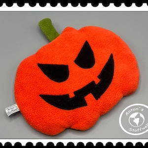 Könnte beinhalten: Ein orangefarbener Plüschkürbis mit einem geschnitzten schwarzen Gesicht und einem grünen Stiel. Der Kürbis hat ein finsteres Grinsen. Eine Halloween-Dekoration.