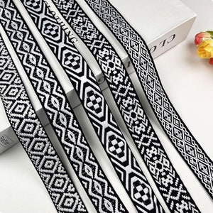 Könnte beinhalten: Vier schwarze und weiße gemusterte Besatzbänder mit geometrischen Mustern. Die Bänder sind fächerförmig angeordnet.