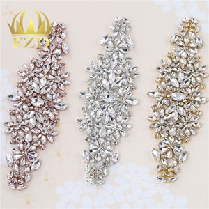 May include: Three rows of rhinestone embellishments in gold, silver, and rose gold. Each row features a cluster of clear rhinestones in a floral design.