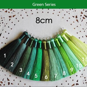 May include: Green Series 8cm tassel trim in 12 shades, ranging from dark green to light green. The tassels are 8 centimeters long and are arranged in a row from darkest to lightest.