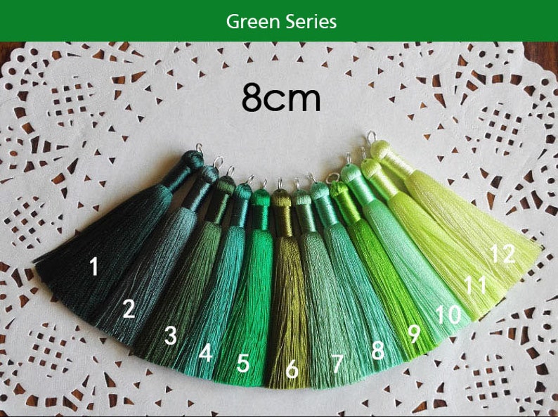 May include: Green Series 8cm tassel trim in 12 shades, ranging from dark green to light green. The tassels are 8 centimeters long and are arranged in a row from darkest to lightest.