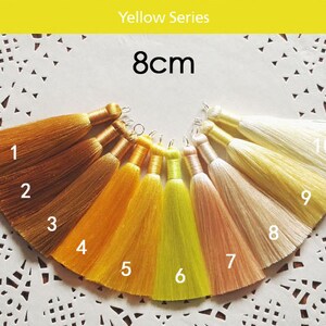 May include: Ten 8cm long tassels in various shades of yellow, orange, and cream. The tassels are numbered 1 through 10. Yellow Series.