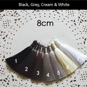 May include: Seven tassel trims in black, dark gray, light gray, cream, and white. The tassels are 8 cm long.