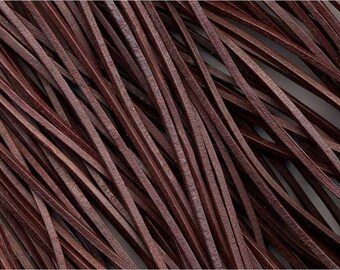 May include: Close-up of a pile of dark brown leather cords. The cords are thin, flat, and appear to be made of genuine leather. The cords are arranged in a diagonal pattern, creating a textured surface.