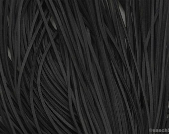 May include: A close-up of a bundle of black leather cords. The cords are arranged in a random pattern, creating a textured background.