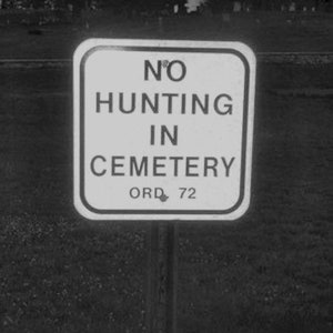 Op de afbeelding: Een zwart-wit bord met de tekst "NO HUNTING IN CEMETERY ORD. 72".