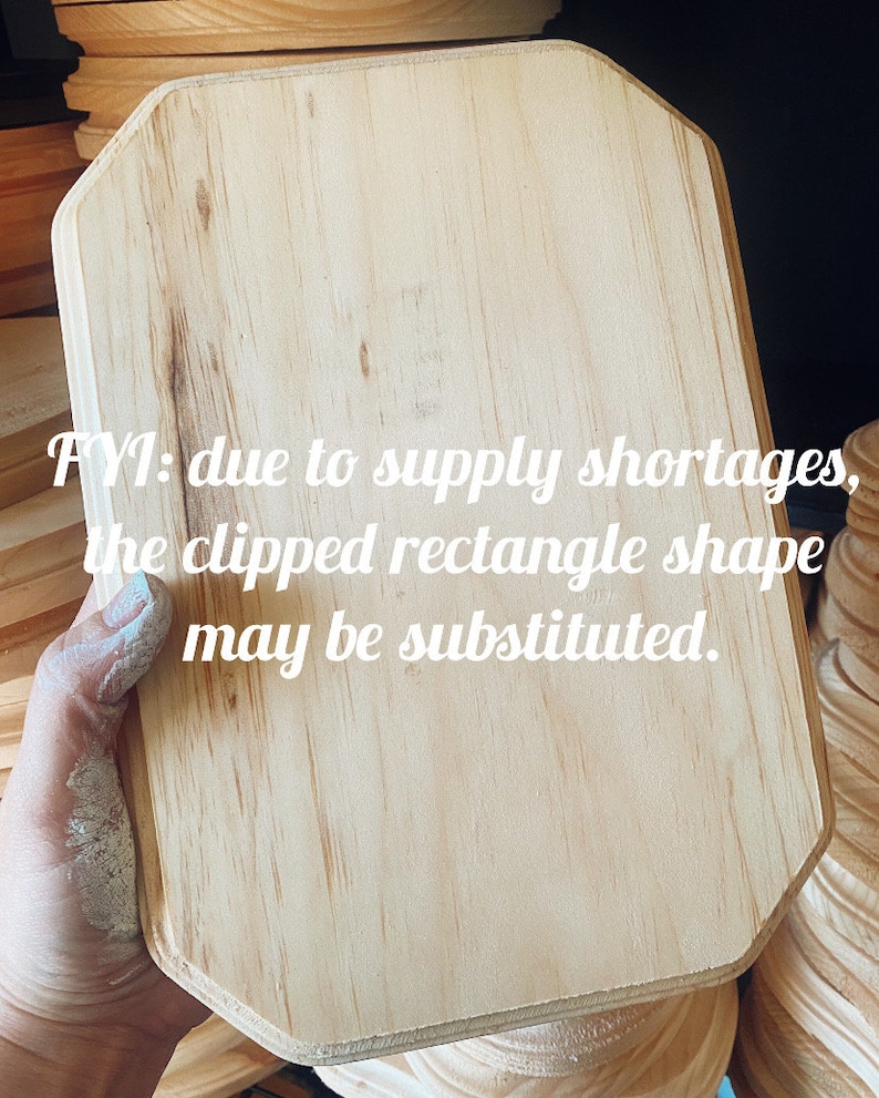 May include: A light-colored, rectangular wooden plaque with clipped corners is held in a hand. The text "FYI: due to supply shortages, the clipped rectangle shape may be substituted" is visible on the plaque.