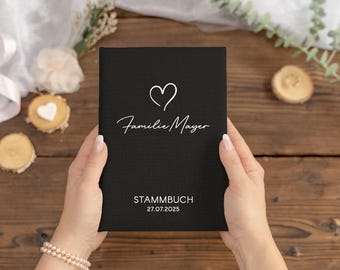 Op de afbeelding: Zwart hardback boek met een wit hart en de tekst "Familie Mayer" en "STAMMBUCH 27.07.2025" op de voorkant.