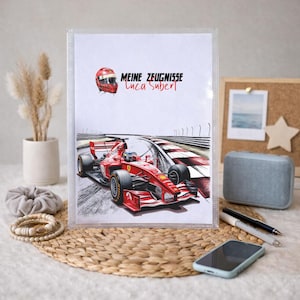 Könnte beinhalten: Ein transparenter Ordner mit Rennsport-Design. Das Kunstwerk zeigt einen roten Rennwagen auf einer Rennstrecke, einen roten Helm und den Text "MEINE ZEUGNISSE Luca Subert" in Schwarz und Rot. Der Ordner liegt auf einer gewebten Matte.