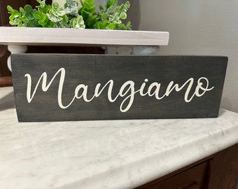 May include: A dark gray wooden sign with the word "Mangiaimo" written in white cursive lettering.