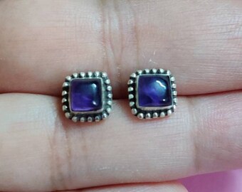May include: A pair of silver stud earrings with square-shaped amethyst gemstones.