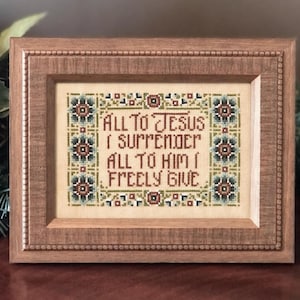 May include: A framed cross-stitch with the words "ALL TO JESUS I SURRENDER ALL TO HIM I FREELY GIVE" in a decorative font. The cross-stitch is framed in a wooden frame with a detailed border. The text is in shades of brown, green, and blue.
