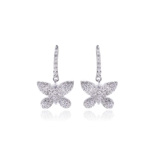 May include: A pair of silver-toned butterfly earrings. Each earring features a butterfly-shaped pendant encrusted with small, clear gemstones. The earrings have a dangling design with a post and hook closure.