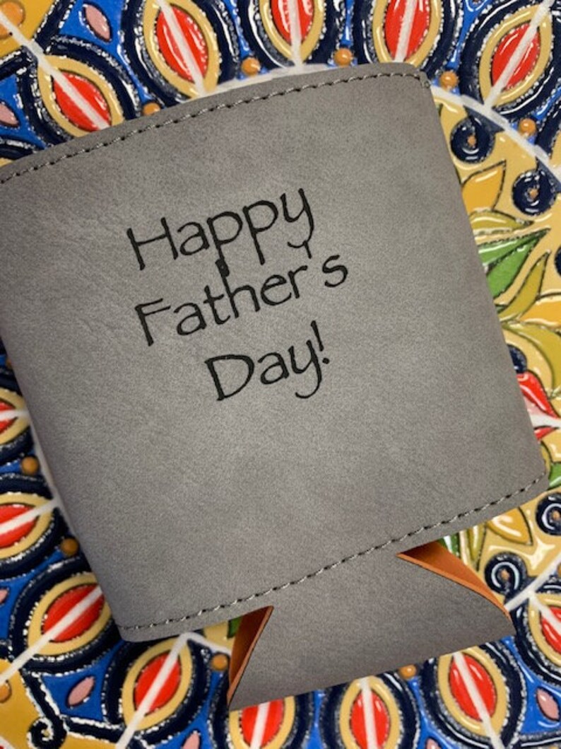 May include: Gray fabric can cooler with a stitched seam and a brown leather handle. The cooler has the text "Happy Father's Day!" printed on the front.