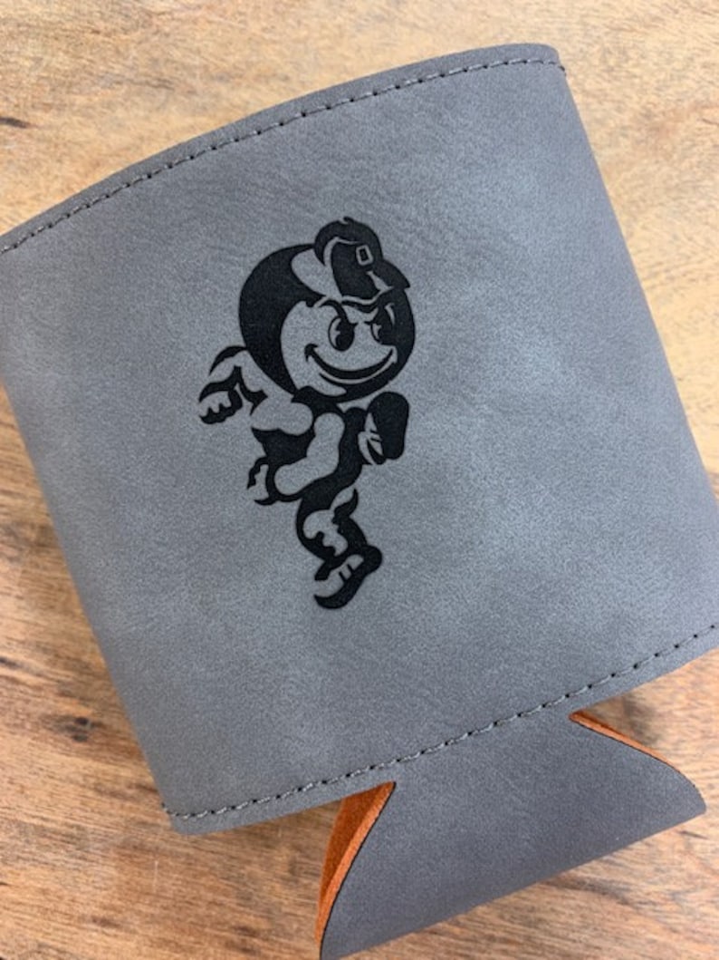 May include: Gray leather can cooler with a black and white cartoon mascot wearing a hat. The mascot is running and has a happy expression.
