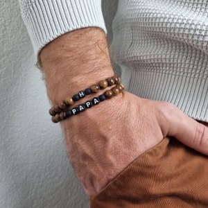 May include: Two beaded bracelets with black beads and white letter beads spelling "PAPA" and "H".