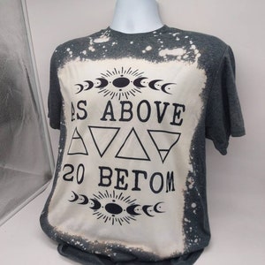 May include: A gray t-shirt with a bleached design featuring the text "As Above So Below" with a sun and moon symbol above and below the text.