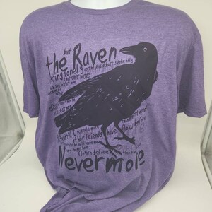 Op de afbeelding: Paars T-shirt met een zwarte raaf afbeelding en de tekst "the Raven" en "Nevermore".
