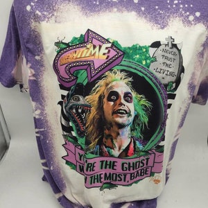 May include: Purple and white tie-dye t-shirt with a graphic print of a character from the movie Beetlejuice. The graphic includes the text "New Time" and "You're the Ghost with the Most, Babe".