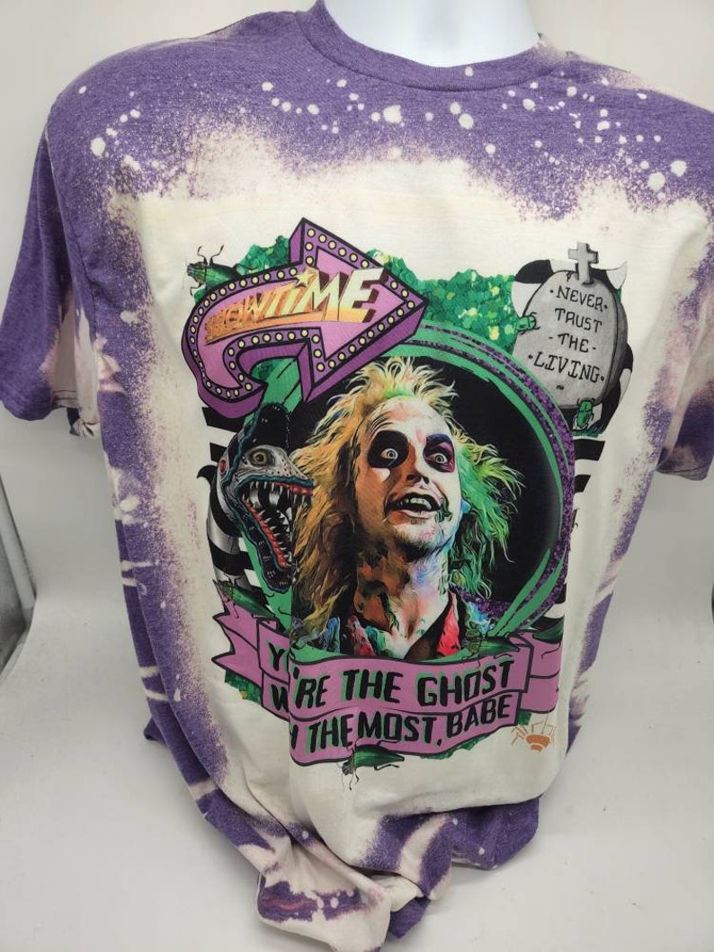 May include: Purple and white tie-dye t-shirt with a graphic print of a character from the movie Beetlejuice. The graphic includes the text "New Time" and "You're the Ghost with the Most, Babe".