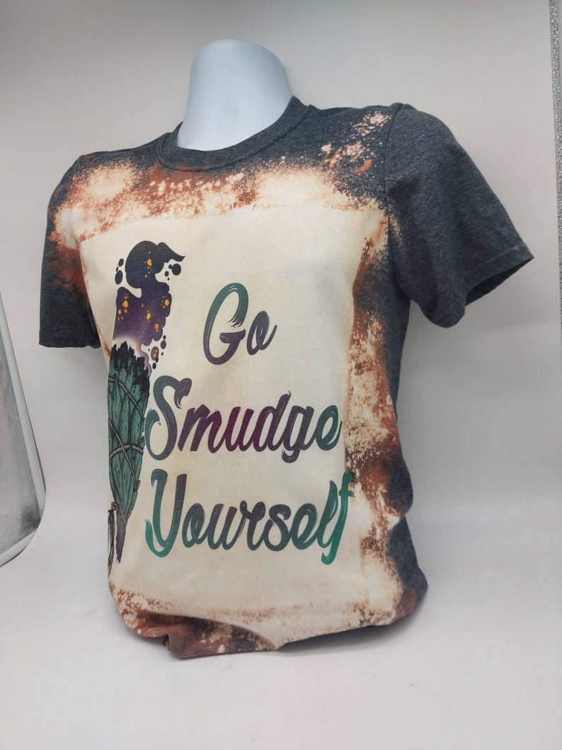 May include: A grey t-shirt with a bleached design featuring a sage bundle and the text "Go Smudge Yourself".