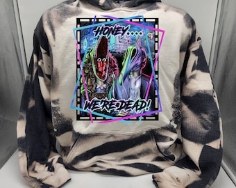 Könnte beinhalten: Ein tie-dye Hoodie in Schwarz und Weiß mit einem Grafikdruck von zwei Figuren mit dem Text "Honey... We're Dead!" in einem neonrosa und blauen Rahmen.