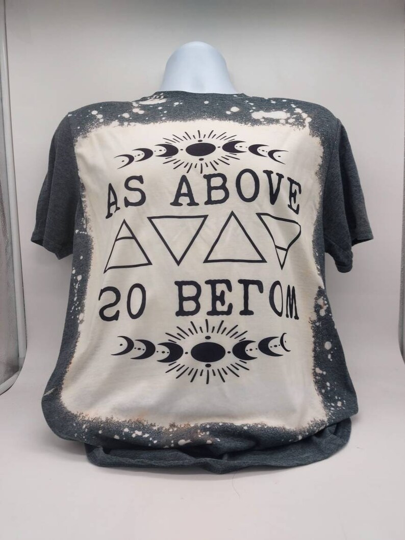 May include: A gray t-shirt with a bleached design featuring the text "As Above So Below" with a crescent moon and sun graphic.