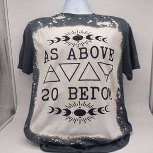 May include: A gray t-shirt with a bleached design featuring the text "As Above So Below" with a crescent moon and sun graphic.