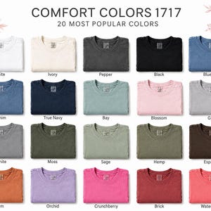 May include: A colour chart for Comfort Colors 1717 t-shirts displaying 20 folded shirts in various shades including white, ivory, pepper, black, blue jean, denim, true navy, bay, blossom, grey, granite, moss, sage, hemp, espresso, yam, orchid, crunchberry, brick, and watermelon.