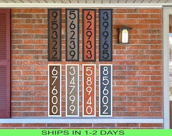 May include: Six wooden house number signs with black numbers on a brick wall. The numbers are 9532, 5623, 6293, 3965, 6760, 3479, 5894, and 8560.