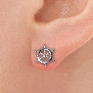 Peut inclure: Boucle d'oreille en forme de volant de bateau en argent. La boucle d'oreille est une petite réplique détaillée d'un volant de bateau.