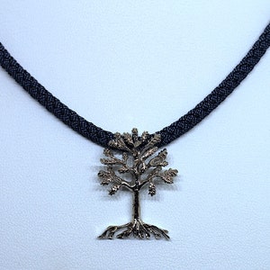 Op de afbeelding: Een zilveren levensboom hangerketting met een zwart gevlochten koord.