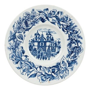 May include: A round white ceramic plate featuring a blue transferware design. The center depicts a detailed illustration of a large church building with trees. The rim is decorated with a continuous wreath of blue orchids and foliage.