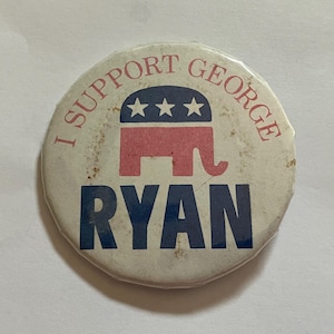 May include: A round, vintage political campaign button with the text "I SUPPORT GEORGE RYAN". The button features a red elephant symbol with three blue stars, a symbol of the Republican Party.
