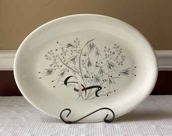 May include: A white oval serving platter with a silver floral design. The design features delicate sprigs of flowers and leaves.