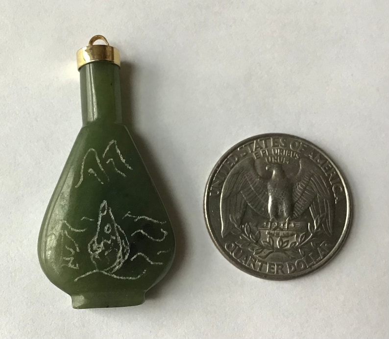 May include: A small green jade bottle pendant with a gold cap. The bottle is carved with a mountain scene and a bird in flight. The pendant is about the size of a US quarter.