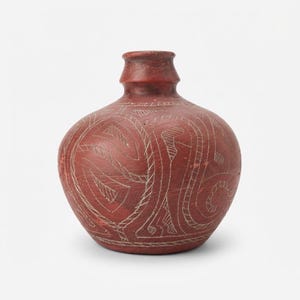 May include: A terracotta-colored ceramic vase with a rounded body and a narrow neck. The surface features intricate, hand-etched white line patterns consisting of swirling shapes and geometric hatching, creating a textured appearance.