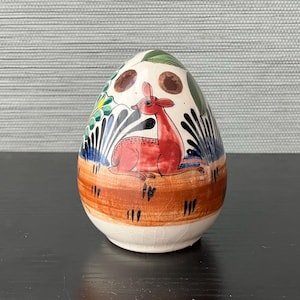 May include: A white ceramic mug with a black handle and the text "But First, Coffee" in a handwritten style. The mug is on a white surface. The mug is approximately 4 inches tall.