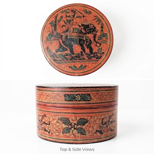 May include: A round, lidded box featuring a vibrant orange-red base with intricate black and green hand-painted details. The lid displays an elephant with a rider, while the sides show floral motifs and figures. Text reads: Top & Side Views.