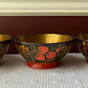 May include: Three black and gold bowls with red and gold floral designs. The bowls are made of wood and have a glossy finish.
