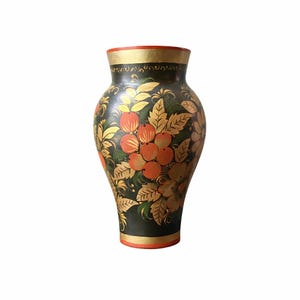 May include: A hand-painted, decorative vase with a dark green base. The vase features a floral design with orange berries, gold leaves, and accents. The rim and base have gold and orange trim. A unique piece for home decor.