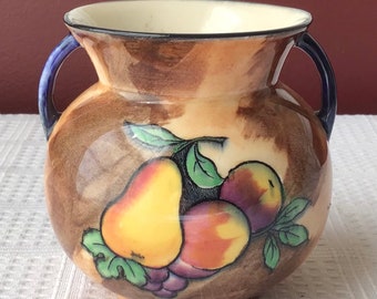 May include: A brown ceramic vase with blue handles and a painted design of pears and grapes. The vase has a mottled brown glaze.