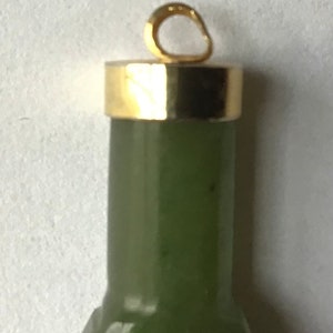 May include: A green jade pendant with a gold top and a gold loop for hanging.