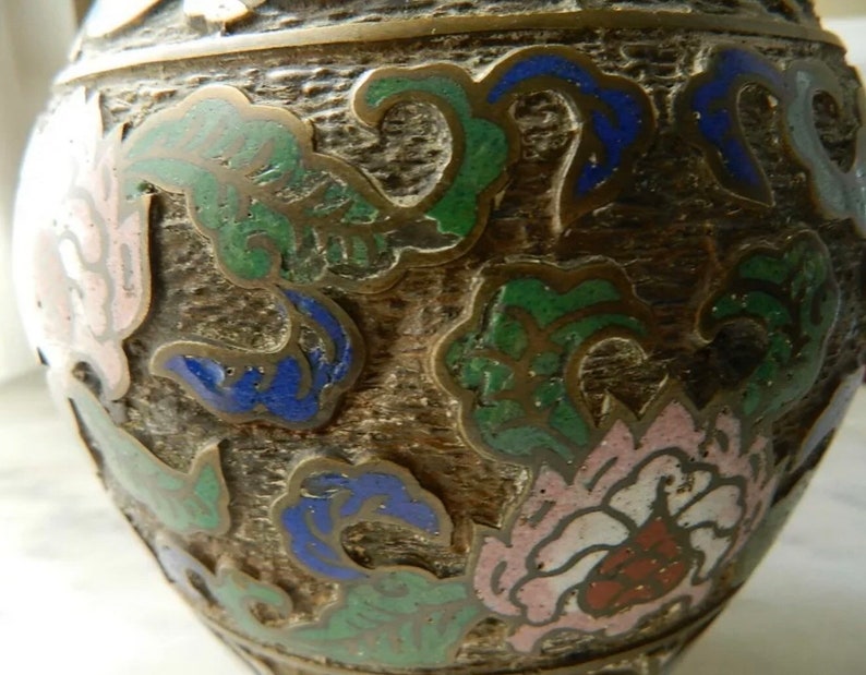 K&ouml;nnte beinhalten: Eine braune Keramikvase mit floralem Design. Die Vase ist mit gr&uuml;nem, blauem, rosa und wei&szlig;em Email verziert.