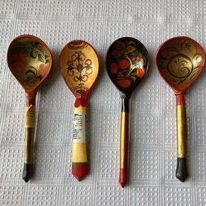 May include: Four wooden spoons with hand-painted designs. The spoons are red, yellow, and black with floral and geometric patterns.