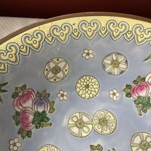 May include: A large, round, blue and white ceramic bowl with a decorative floral pattern. The bowl has a yellow rim with a repeating heart design.
