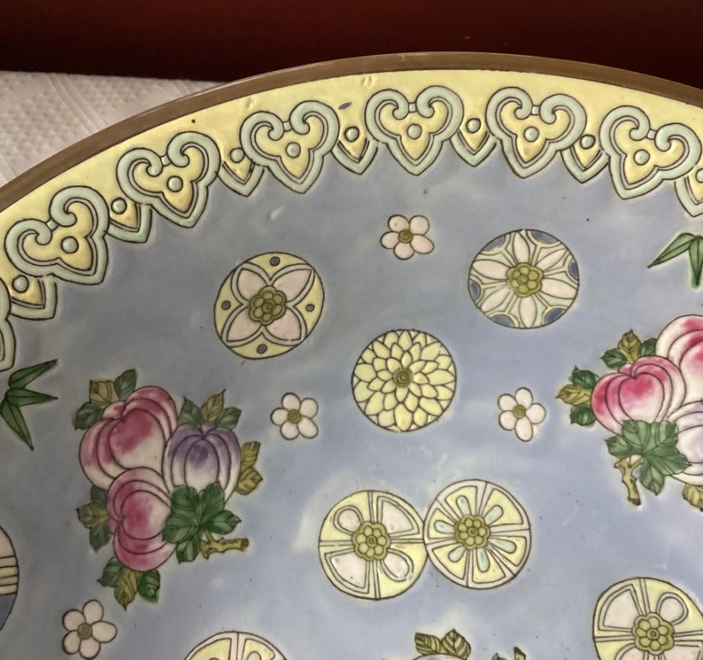 May include: A large, round, blue and white ceramic bowl with a decorative floral pattern. The bowl has a yellow rim with a repeating heart design.