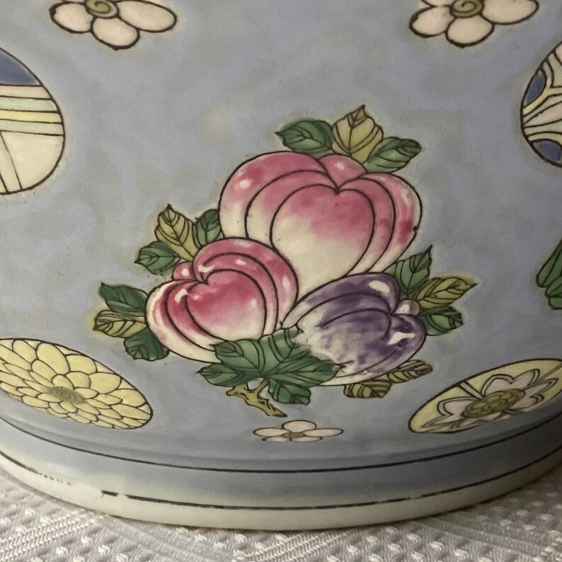 May include: A blue ceramic bowl with a floral design. The bowl features pink, purple, and yellow flowers with green leaves. The bowl has a white rim.